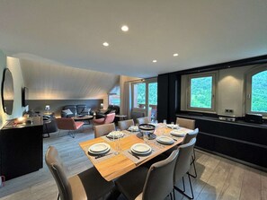 A modern dining area with a wooden table set for four, surrounded by chairs. - Spacious apartment mountain view - 8 guests (Méribel)
