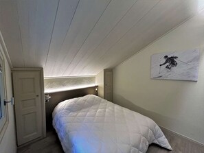 A bedroom with a bed, a door, a window, and a wall-mounted picture. - Spacious apartment mountain view - 8 guests (Méribel)