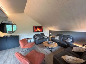 A modern living room with a fireplace, leather sofas, and a round coffee table. - Spacious apartment mountain view - 8 guests (Méribel)
