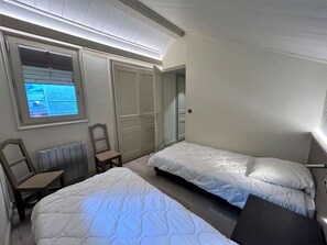 Un dormitorio con dos camas, una silla, un escritorio y una televisión.