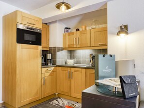 A modern kitchen with wooden cabinets, a built-in oven, and a coffee maker. - Apartment with wellness - 4 guests (Les Saisies)