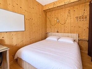 A wooden room with a bed, a whiteboard, and string lights. - QUIR301 - Profitez d’un séjour au calme, à deux pas des pistes (Mont-de-Lans)