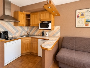 A compact kitchen with wooden cabinets, a microwave, a coffee maker, and a dishwasher. - QUIR301 - Profitez d’un séjour au calme, à deux pas des pistes (Mont-de-Lans)