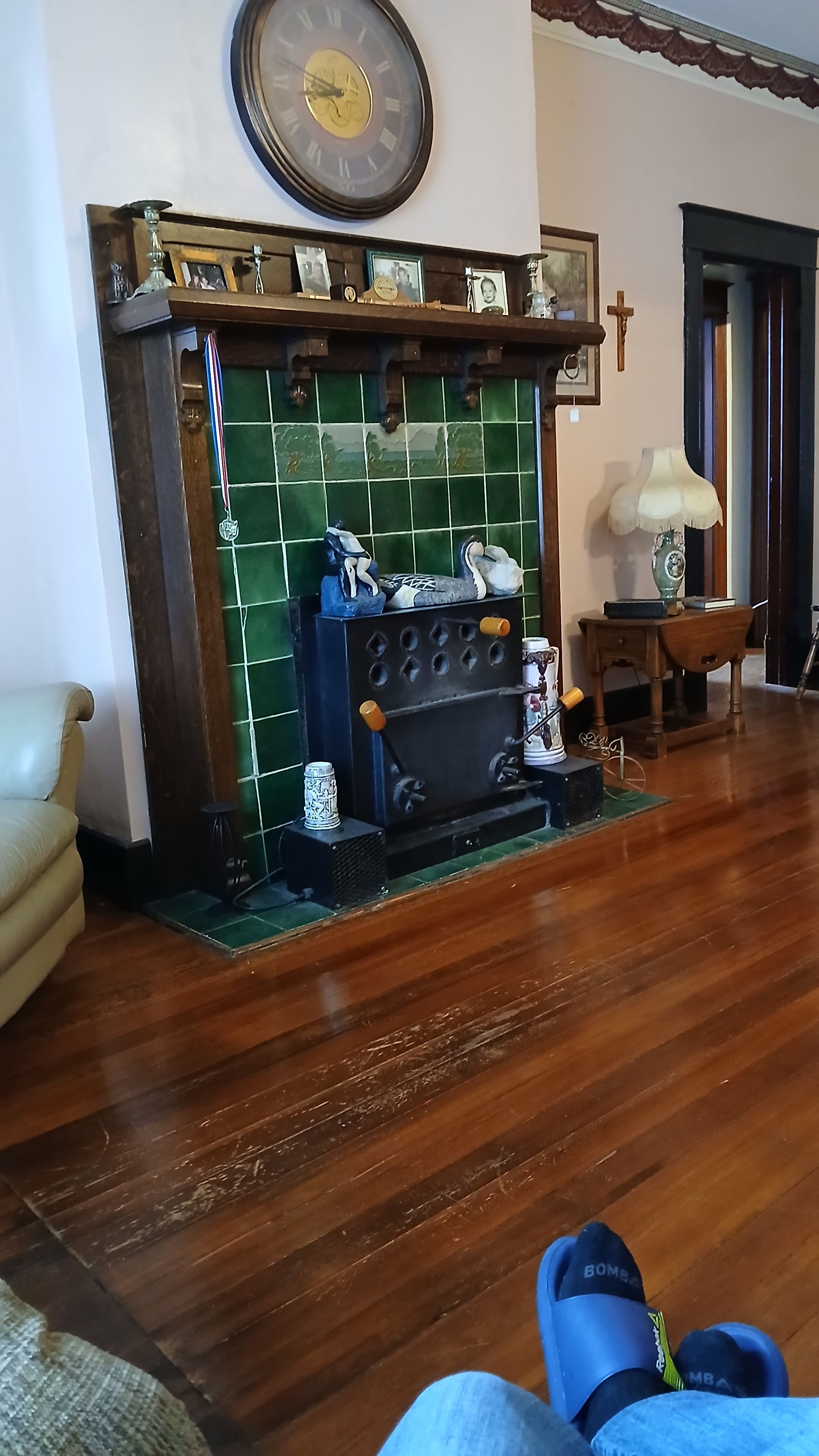 Une pièce avec une cheminée, un plancher en bois, une chaise et une table avec une lampe.