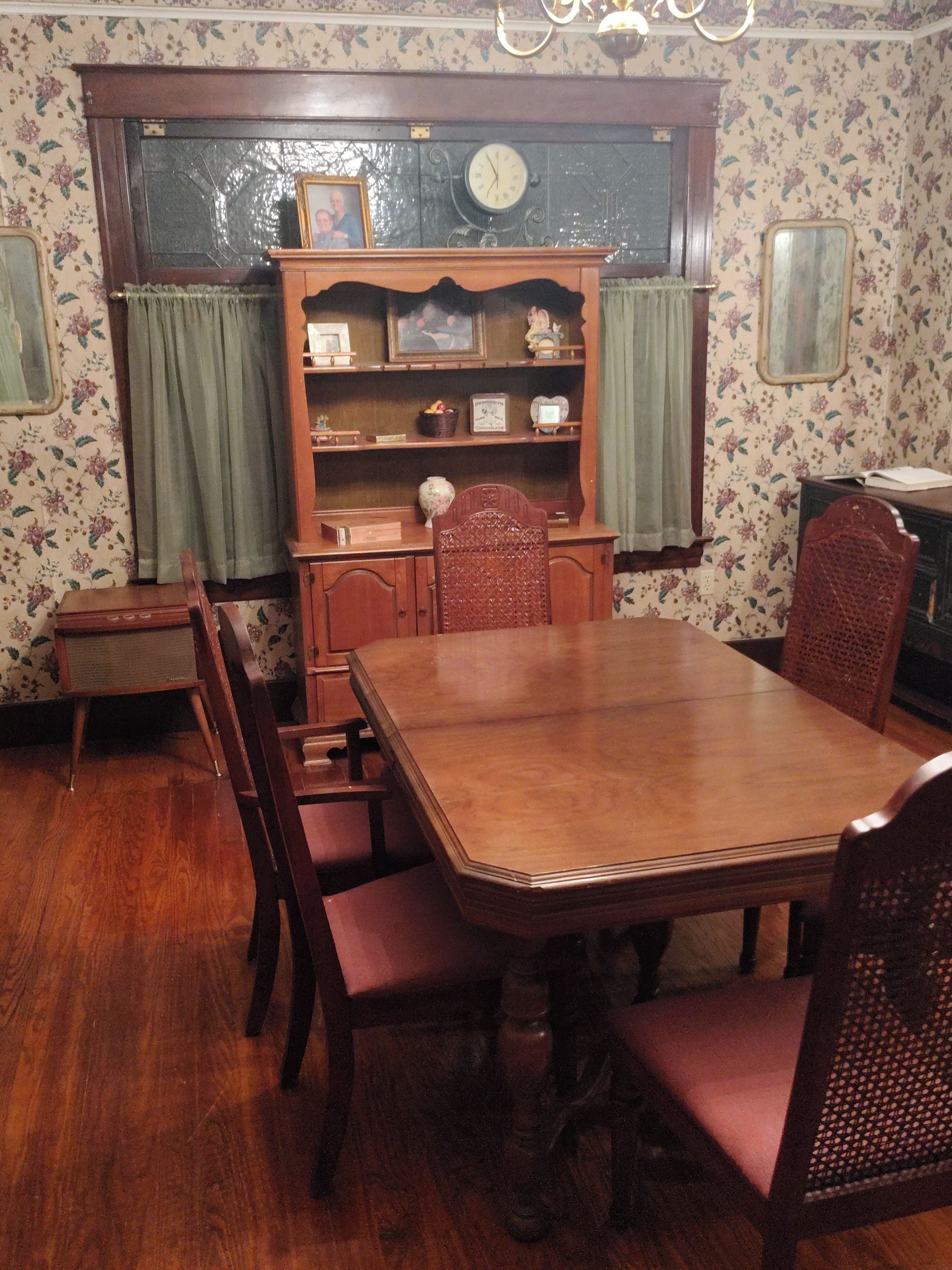 Una sala da pranzo con tavolo e sedie in legno, una libreria e un orologio appeso al muro.