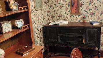 A room with a wooden desk, a chair, a bookshelf, and a wall clock.