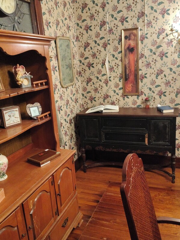 A room with a wooden desk, a chair, a bookshelf, and a wall clock.