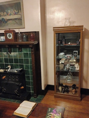 Een kamer met een open haard, een houten kast met glazen deuren en een schilderij erboven.