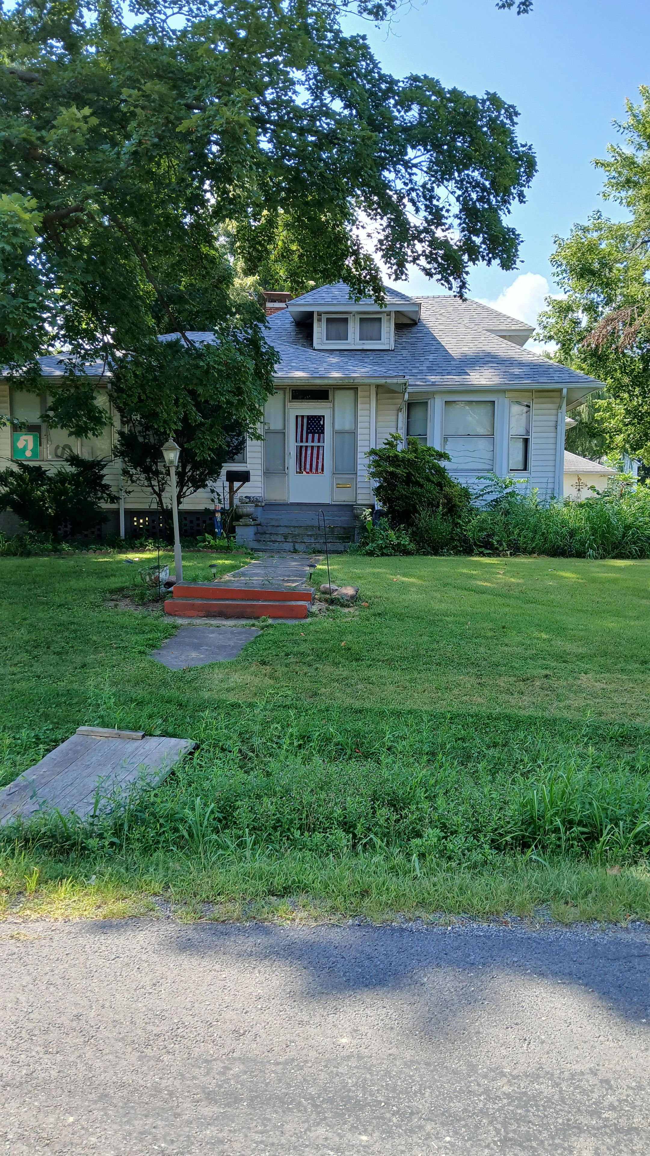 A residential house with a front yard, steps leading to the entrance, and a mailbox.