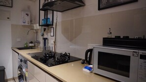 Een keuken met een ingebouwde kookplaat, een magnetron en een wasmachine.