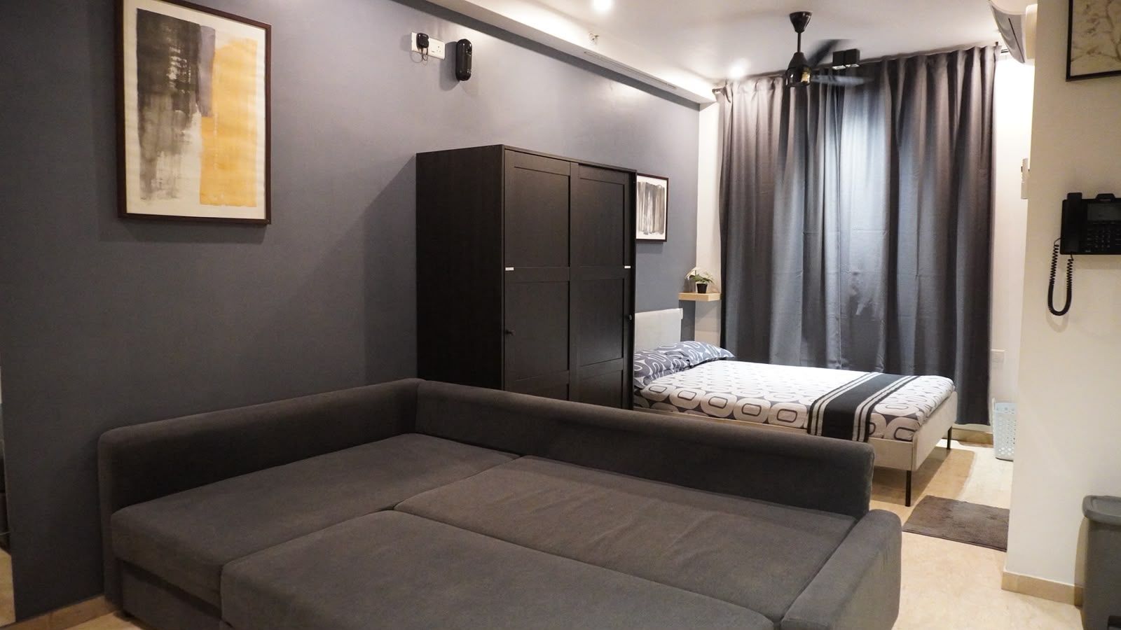 A bedroom with a bed, a wardrobe, a sofa, and a painting on the wall.
