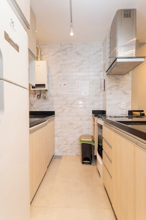 Una cocina compacta con refrigerador, estufa y microondas.