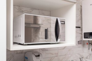 Un horno microondas Panasonic sobre un estante blanco en una cocina con baldosas de mármol.
