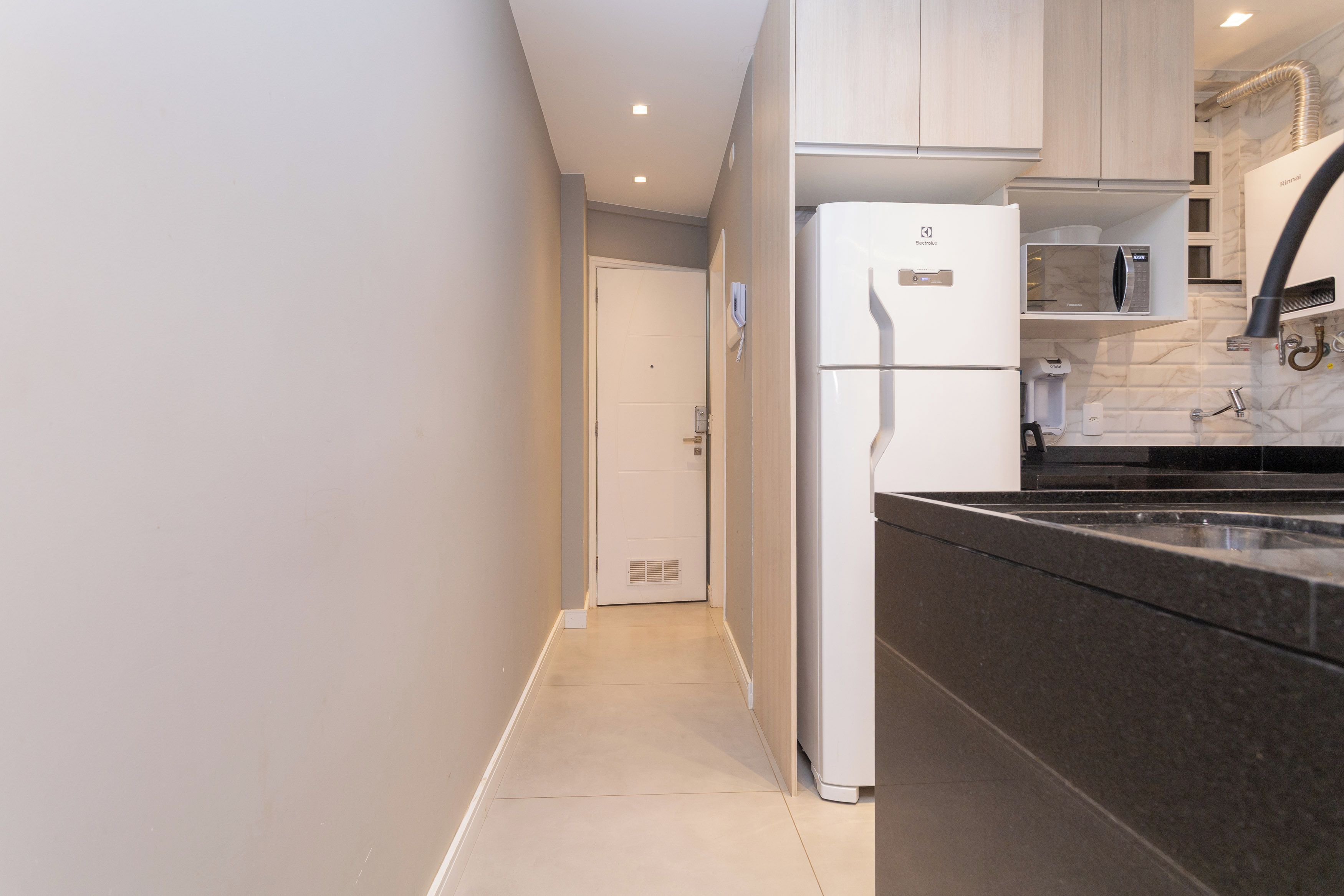 A modern kitchen with a built-in refrigerator, a microwave, and a coffee machine.