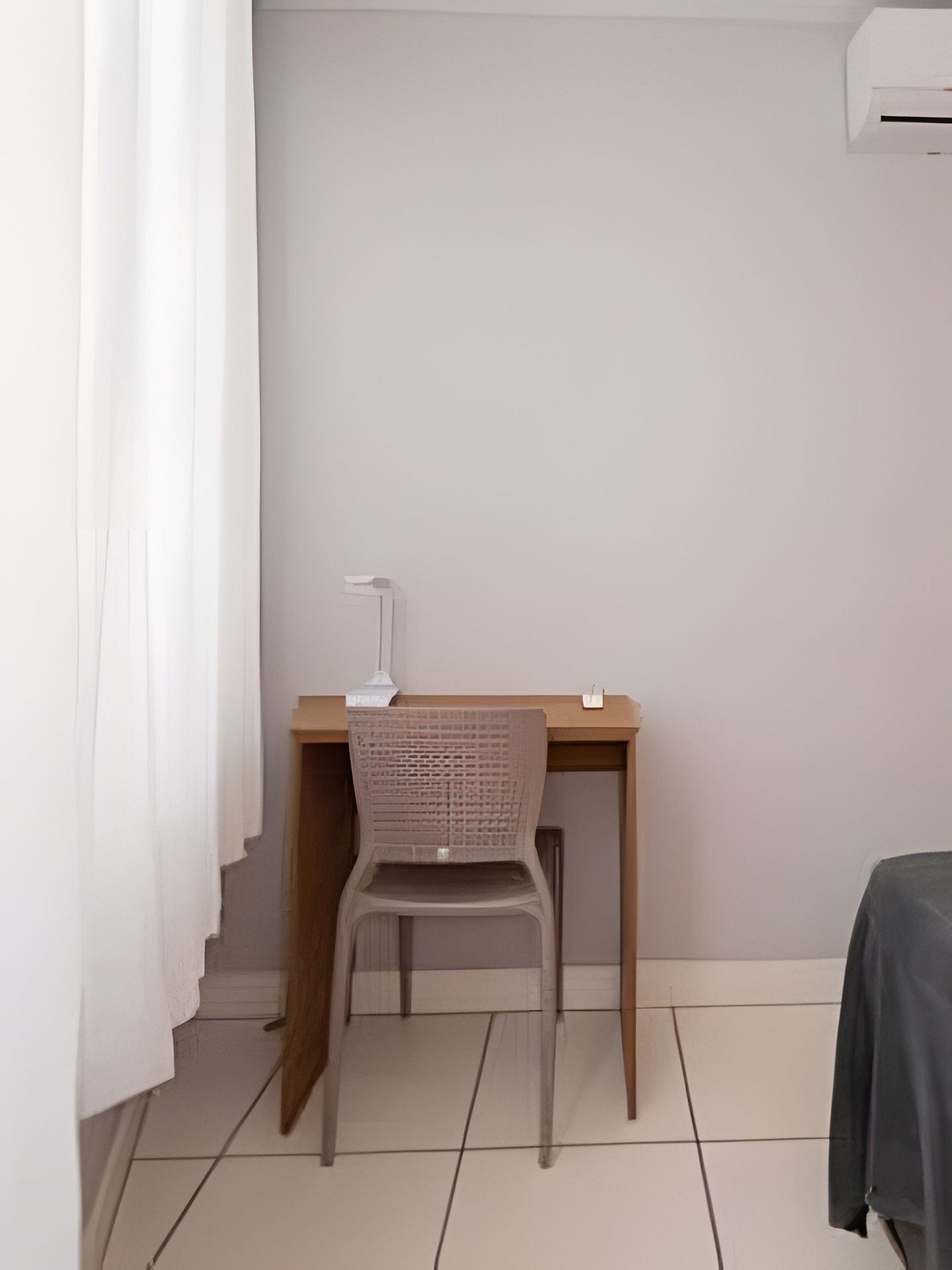 A room with a desk, chair, and an air conditioning unit.