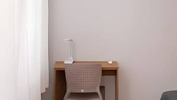 A room with a desk, chair, and an air conditioning unit.