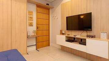 A modern room with a television mounted on a wooden cabinet, a sliding door closet, and a small shelf with decorative items.
