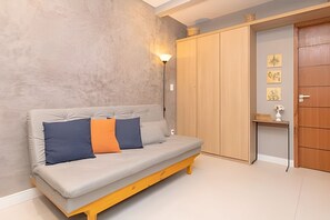A room with a sofa, a wardrobe, and a wall-mounted light fixture. - Edifício Master - Apt 3 minutos da praia (Rio de Janeiro)