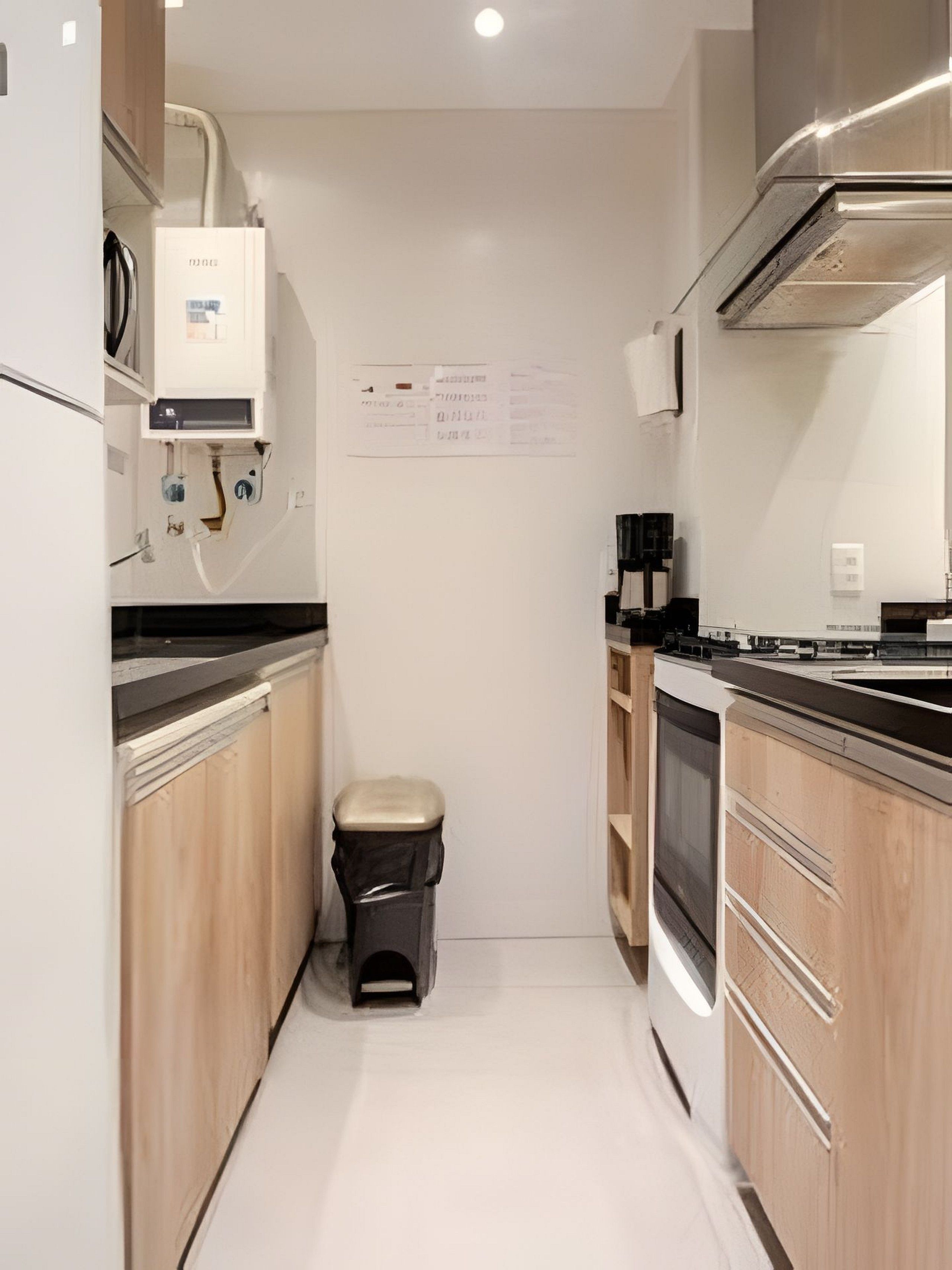 A compact kitchen with wooden cabinets, a stainless steel range hood, and a built-in oven.