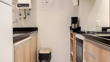 A compact kitchen with wooden cabinets, a stainless steel range hood, and a built-in oven.