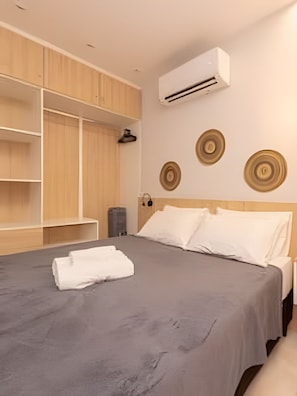 Un dormitorio con cama, armario, aire acondicionado instalado en la pared y paneles decorativos.