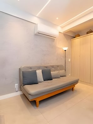 A modern living room with a sofa, a lamp, and a wardrobe. - Edifício Master - Apt 3 minutos da praia (Rio de Janeiro)