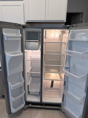 Ein offener Kühlschrank mit mehreren Regalen und einem Wasserspender.