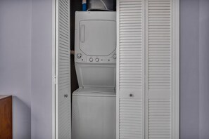 Ein kleinerer Waschraum mit Waschmaschine und Trockner, umgeben von weißen, abgefasteten Türen.