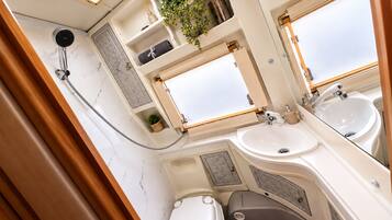Une salle de bain compacte avec une douche, deux lavabos et des toilettes.