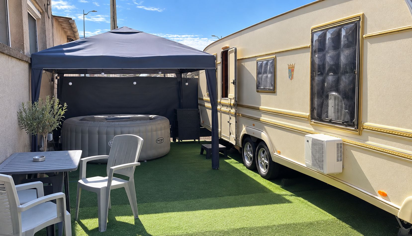 Een camper met een overdekte patio, een jacuzzi en een tafel met stoelen.
