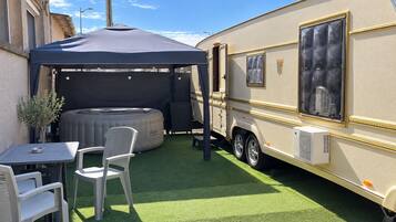 Een camper met een overdekte patio, een jacuzzi en een tafel met stoelen.