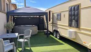 Een camper met een overdekte patio, een jacuzzi en een tafel met stoelen.