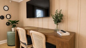 A dining area with a wooden table, two chairs, a television mounted on the wall, and a plant in a vase. - Cozy 1-bedroom condo AC + Parking in Midtown Ocean City Near Convention Center (Ocean City)