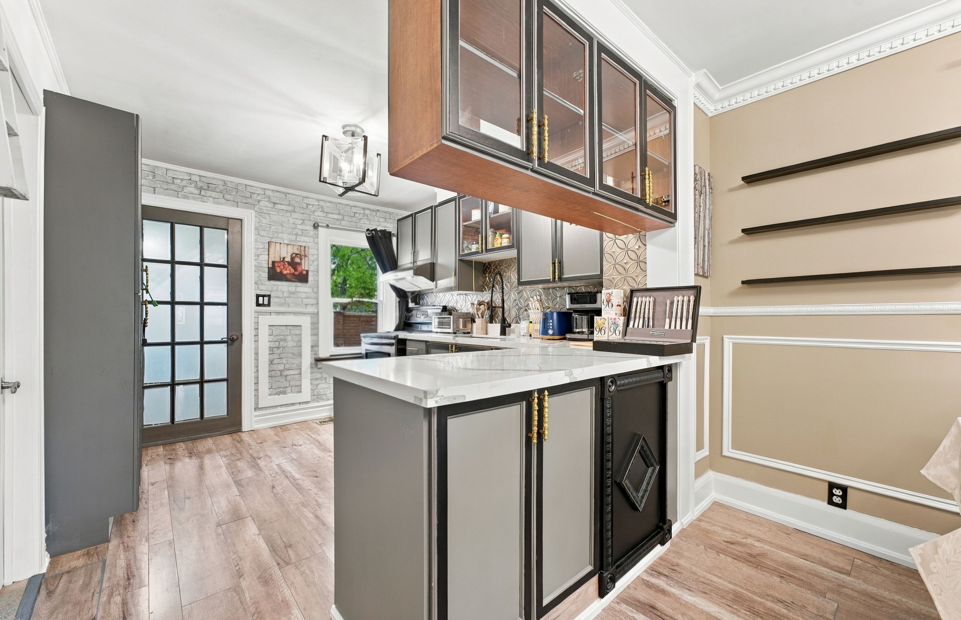 A modern kitchen with a central island, built-in appliances, and a view of the outdoors.