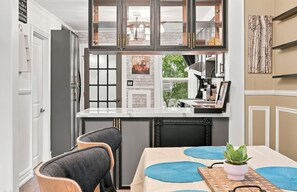 A kitchen with a dining area, featuring a white countertop, black cabinetry, and a view of the outdoors. - Historic Toronto Cottage with Small-Town Charm steps to GO & Subway SIMZEN T.O. (Toronto)