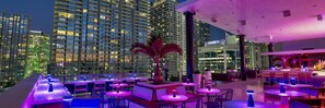 A rooftop bar with multiple tables and chairs, overlooking a cityscape with high-rise buildings. - Casa Bella Miami 3 bedroom 2 full bathrooms in the Centr of Miami (Miami)