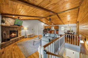 A spacious living area with a stone fireplace, a large gray sofa, and a wooden ceiling. - 5BR Smoky Mountain Escape, Hot Tub, Game Room, Sleeps 14,  10 min to Dollywood (Pigeon Forge)