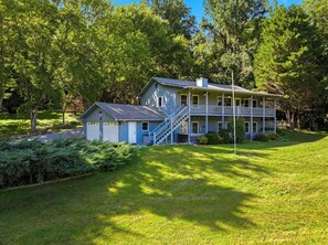A two-story house with a porch and a small attached garage. - 5BR Smoky Mountain Escape, Hot Tub, Game Room, Sleeps 14,  10 min to Dollywood (Pigeon Forge)