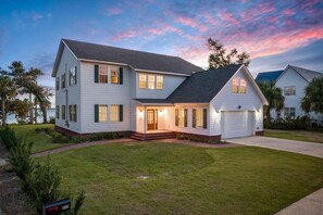 A two-story house with a front porch, a garage, and a well-maintained lawn. - Bay Breeze Retreat | 6BR Group Getaway | Sleeps 15. (Panama City)