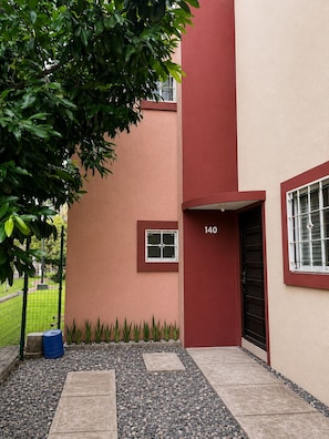A building with a red and beige facade, a black door, and a small window with a white frame.