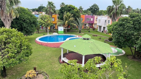 A pool area with a gazebo, surrounded by well-maintained grass and trees.