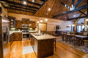 A spacious kitchen with wooden cabinetry, stainless steel appliances, and a large island. - Highland Ridge | 4 Bedrooms, 3 King Suites, Private Hot Tub & Fire Pit (Broken Bow)