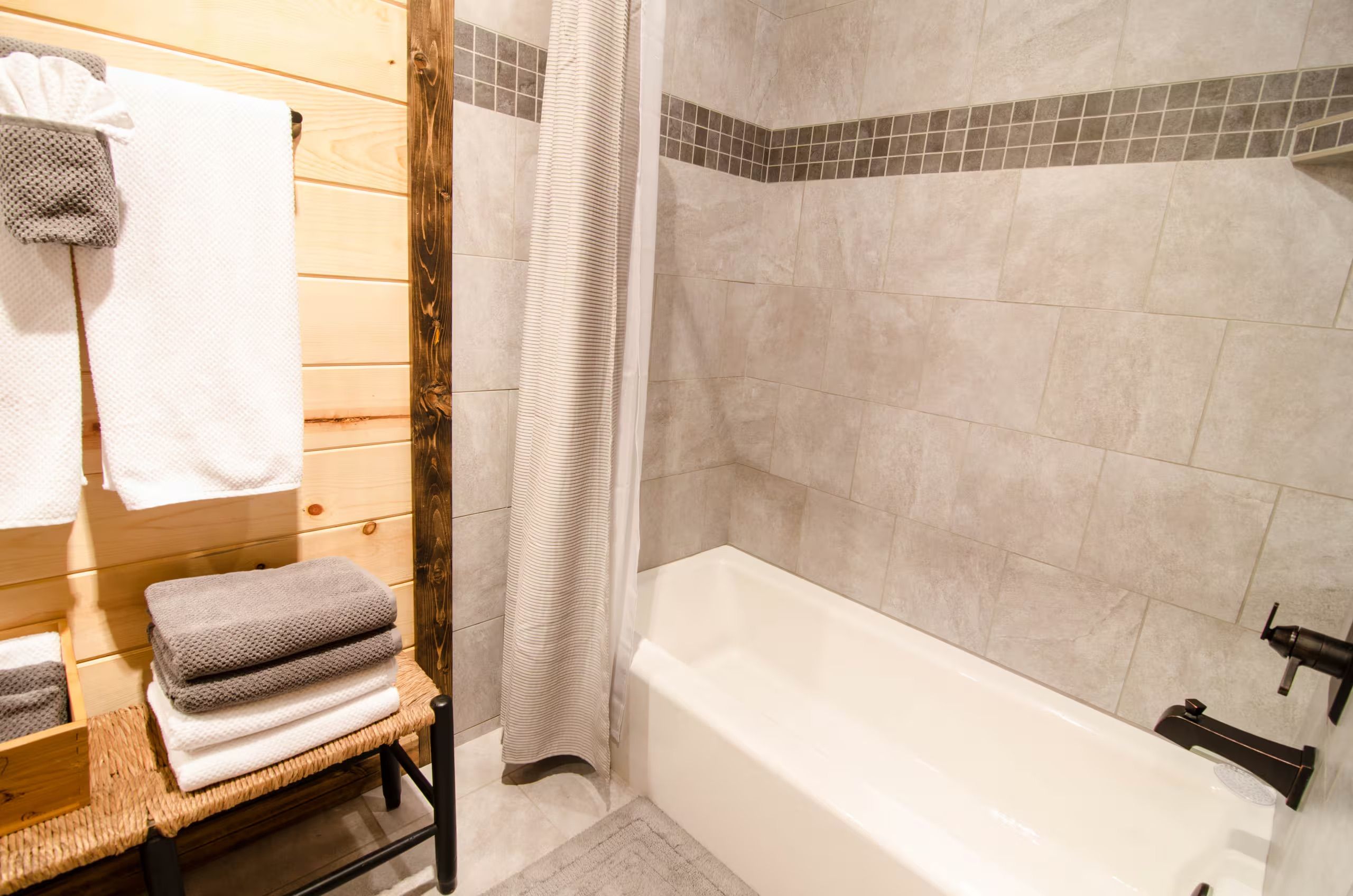 A bathroom with a wooden vanity, a bathtub, and a shower curtain.