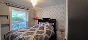 Une chambre à coucher avec un lit, un lustre, une fenêtre et une commode.