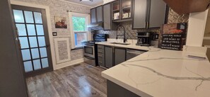 Une cuisine avec un mur en briques, une cuisinière, un évier et un plan de travail en marbre.