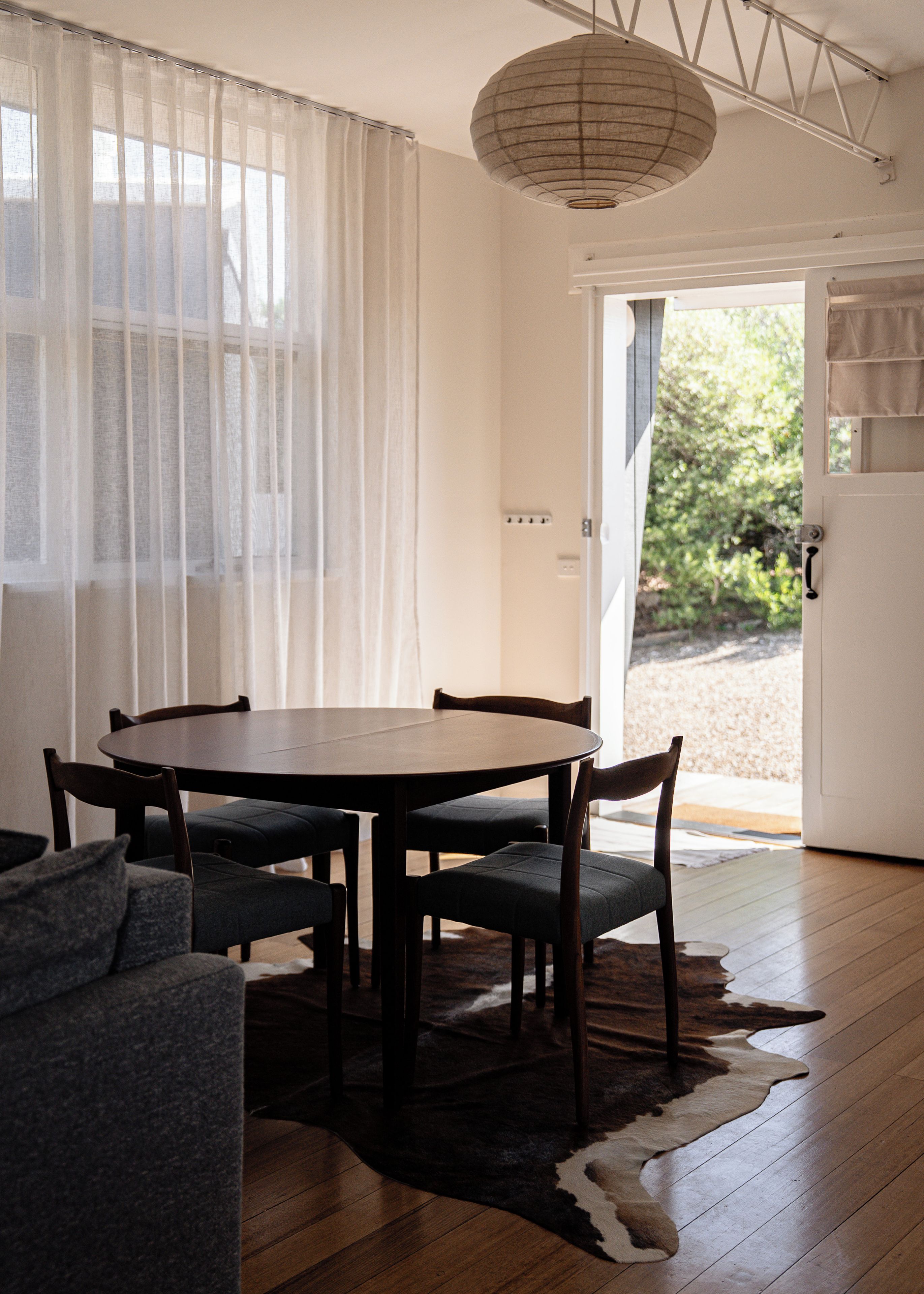 A dining area with a round table, four chairs, a sofa, and a cowhide rug.