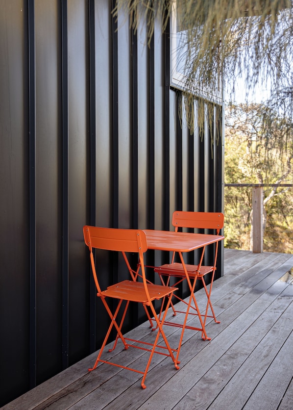 A wooden deck with two orange chairs and a table.