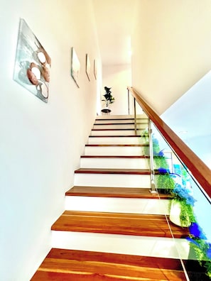 A staircase with wooden steps and glass railings, leading to a landing with a potted plant. - Blue Lion Villa Private Pool 3BR Kamala (Kamala)