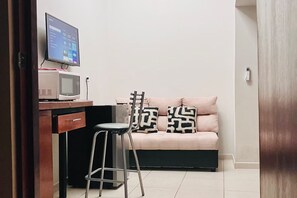 A room with a desk, a computer monitor, a microwave, a sofa with patterned cushions, and a stool. - Casa Madero #2, 1 block from the Malecón (La Paz)