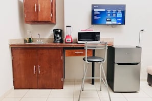 A kitchen with wooden cabinets, a microwave, a blender, a refrigerator, and a TV mounted on the wall. - Casa Madero #2, 1 block from the Malecón (La Paz)